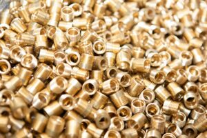 A detailed close-up of a pile of brass screws and nuts with a golden metallic finish.