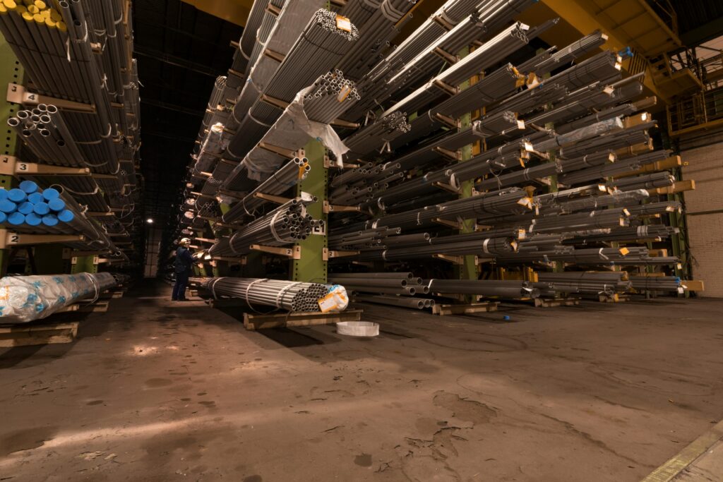 Indoor view of an industrial warehouse filled with steel pipes stored on shelves.