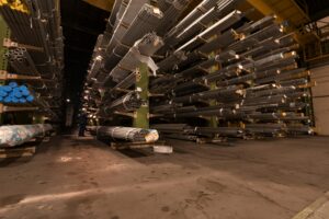 Indoor view of an industrial warehouse filled with steel pipes stored on shelves.